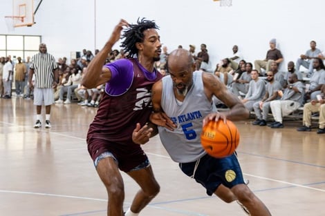 A person playing basketball with another person in the back

Description automatically generated
